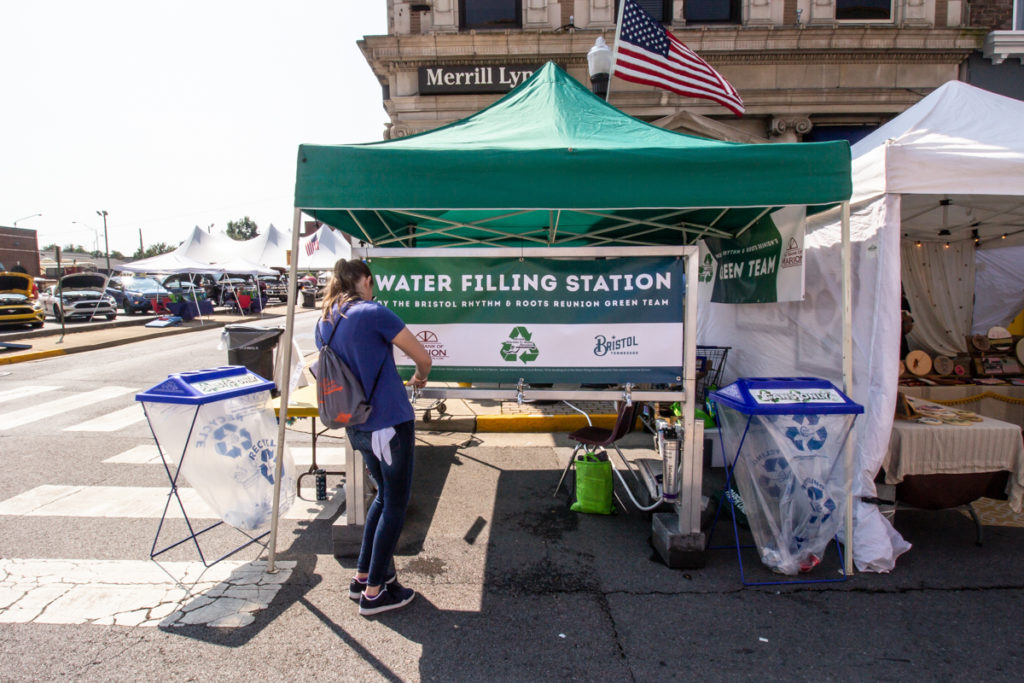 A festivalgoer filling up her bottle at a water refilling station.