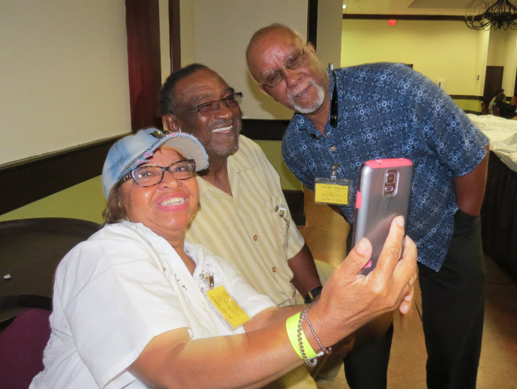 Three alumni post for a selfie together.