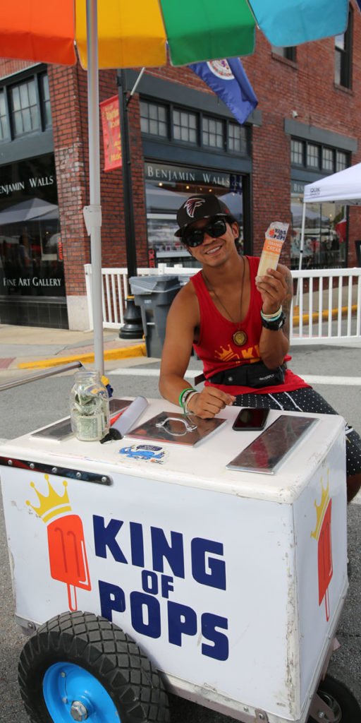 One of the King of Pops vendors holding a pop at the refrigerated cart.