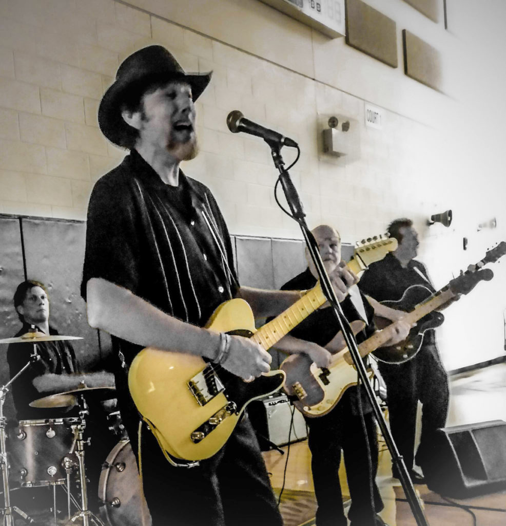 Lightnin' Charlie with his band performing in what looks to be a high school gymnasium.