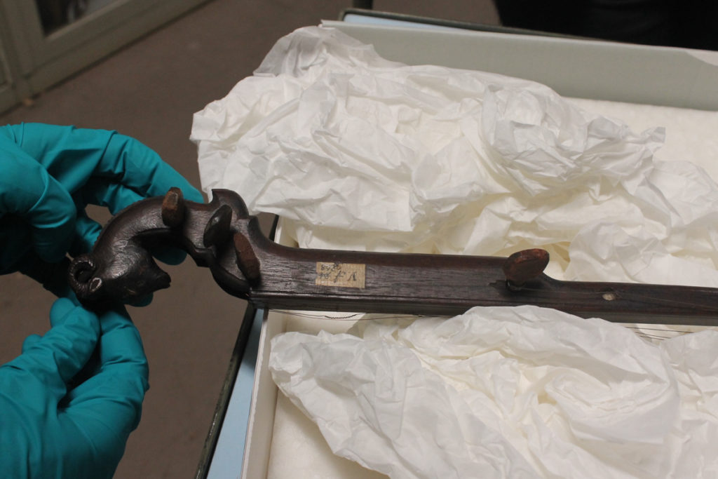 The panja's dark wood peghead, intricately carved with what looks to be a goat head, in the museum archive.