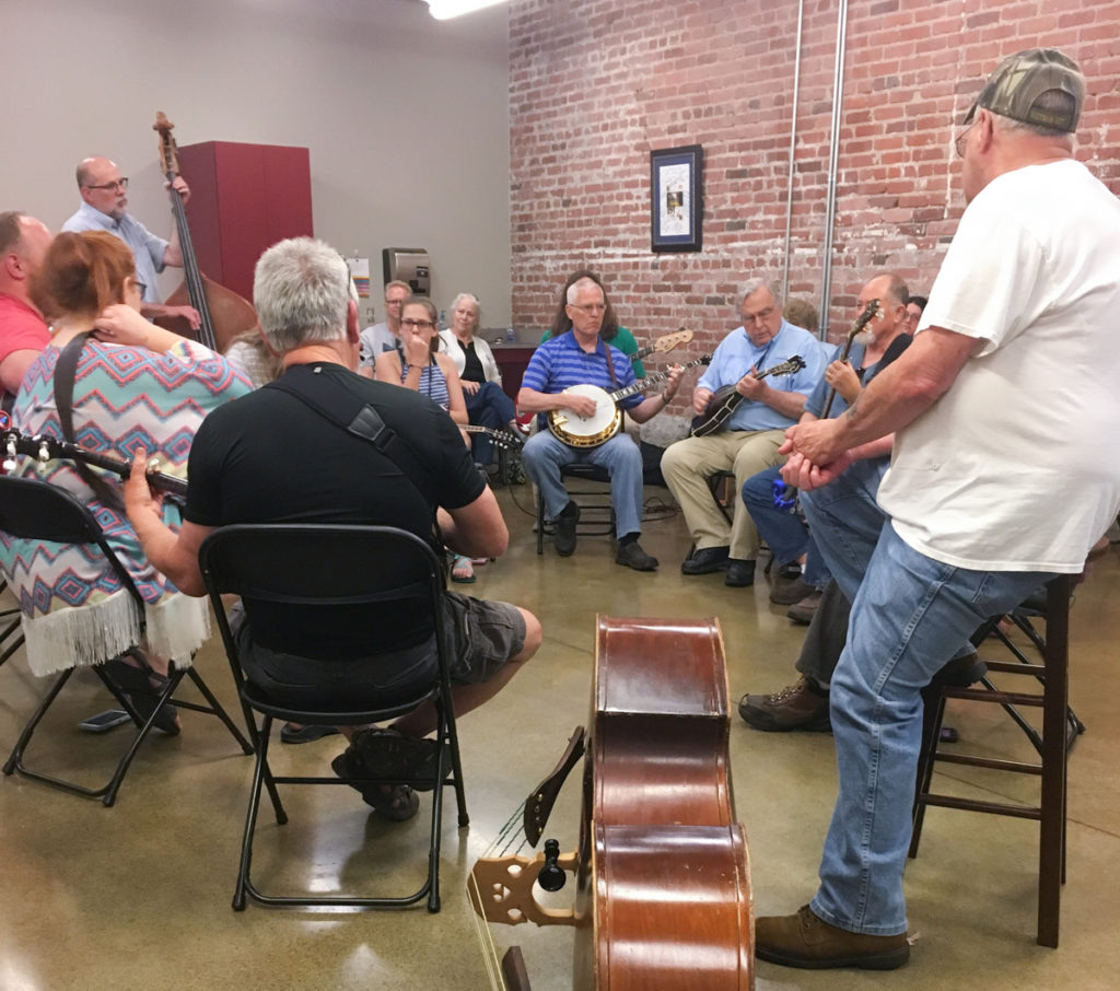 A photograph of a circle of jammers, with a bass on the floor in the foreground.