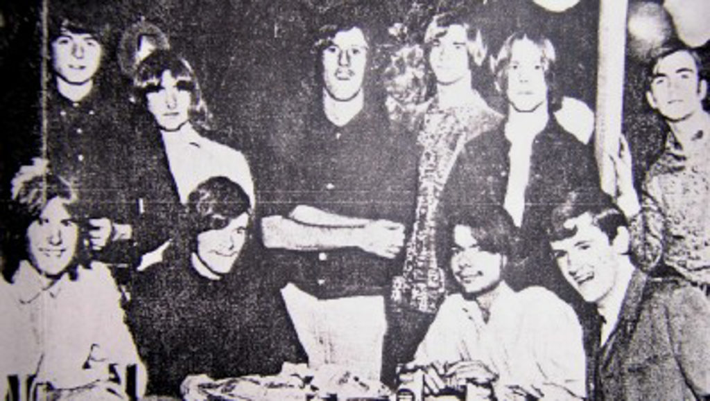 An old black-and-white photograph of several band members together, some sitting and some standing.