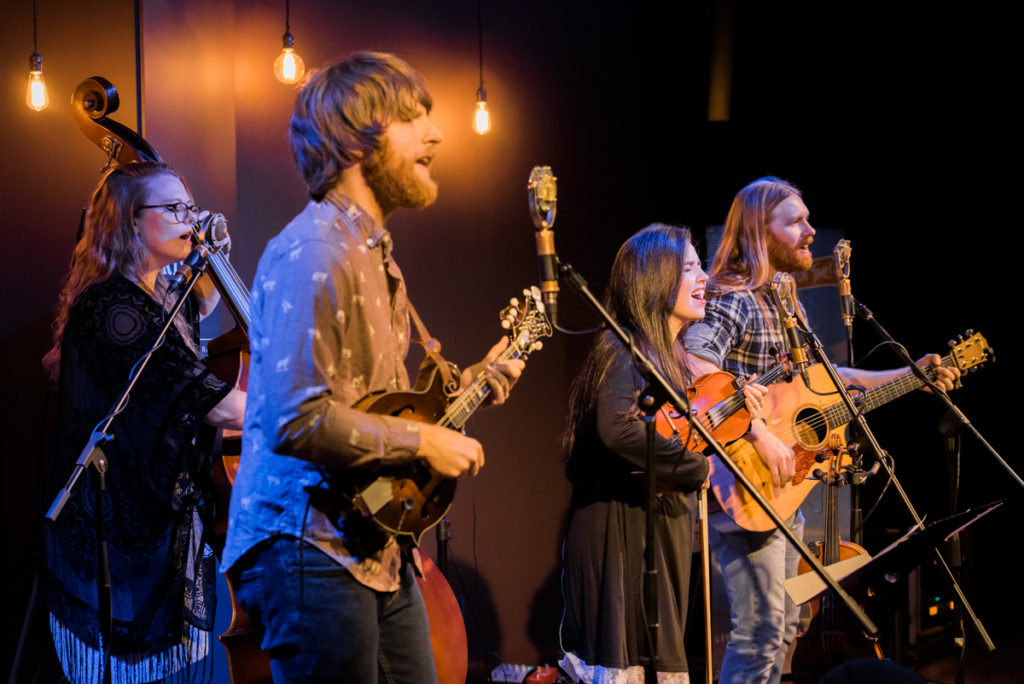 The four band members of The Barefoot Movement playing the bass, mandolin, fiddle and guitar.