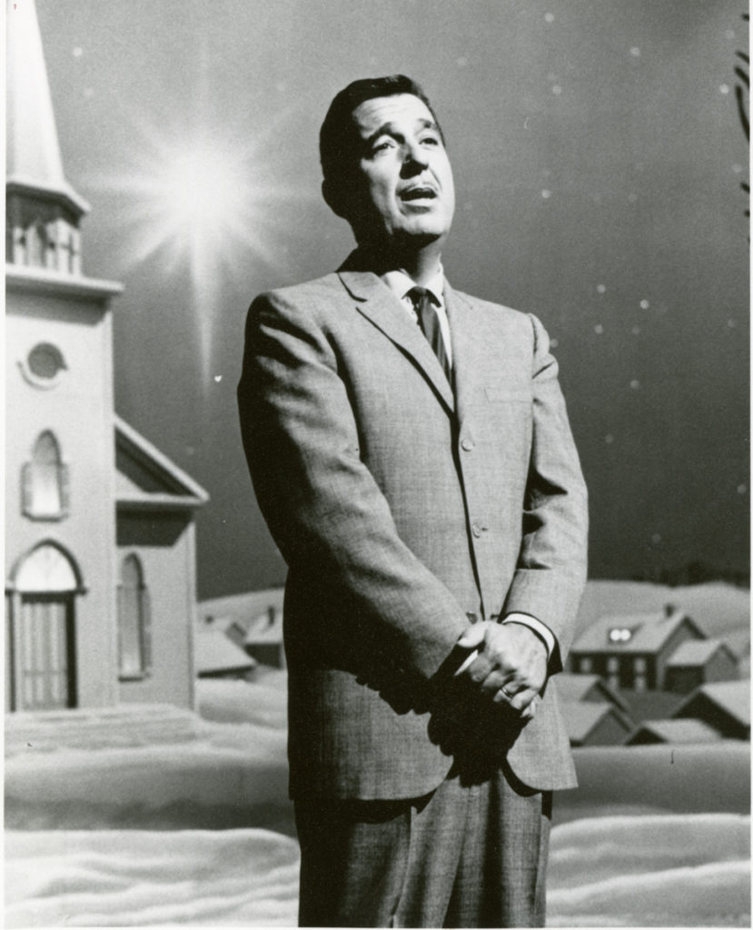 Television still of Tennessee Ernie Ford singing in front of a snowy small-town church background