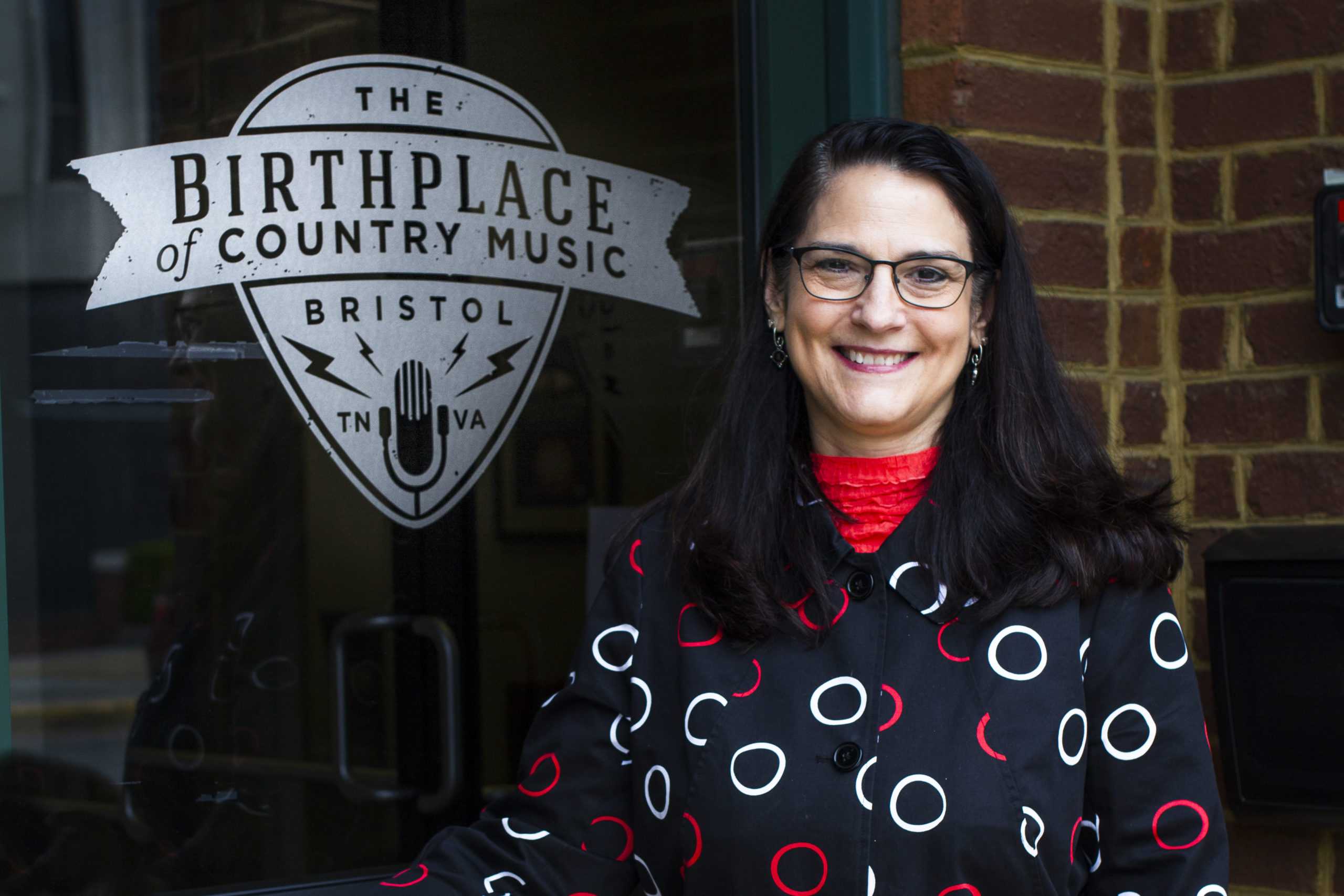 Photo of Paula Hurt standing in front of BCM logo