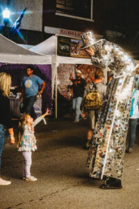 Little girl reaching up to a tall street performer