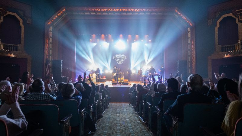 A photo of the darkened Paramount Bristol theater with the stage illuminated in lights.