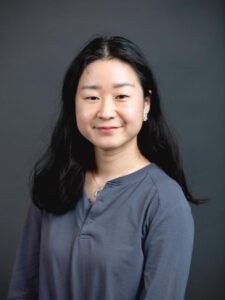 Image of a young Chinese-American woman with long black hair and wearing a grey long sleeve shirt. 