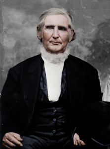 A picture of Benjamin Franklin White. He is an older man, sitting in a three-piece suit, with white, wispy hair and a beard around the base of his neck.