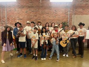 A group of children, holding instruments and wearing matching shirts, at the Birthplace of Country Music Museum's Pick Along Summer Camp.