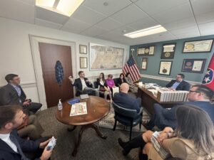 Group of people sitting in various chairs in a formal office setting.