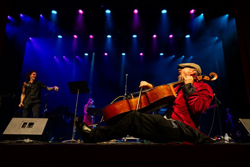 Dave Eggar lying on the stage playing cello at Paramount Bristol during his set at Bristol Rhythm & Roots Reunion 2025.